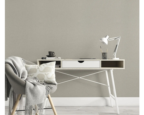 Raumszene mit Schreibtisch, Stuhl mit Decke und Kissen vor einer strukturierten Tapete