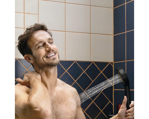 Mann benutzt eine Handbrause im Badezimmer