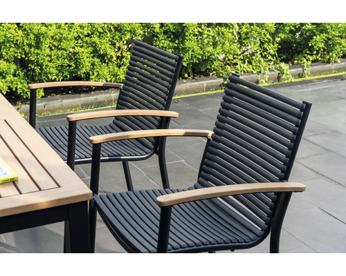 Zwei Gartenstühle mit Armlehnen aus Holz und schwarzen Metallrahmen stehen neben einem Gartentisch.