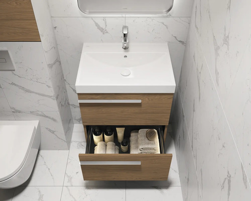 Badezimmer mit Waschbeckenunterschrank, offenem Schubfach und Armatur vor einer gefliesten Wand.