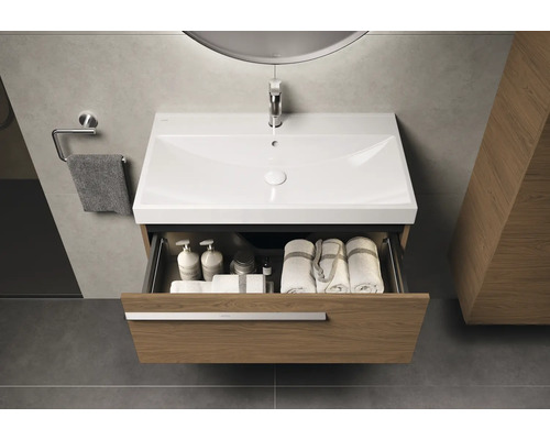 Waschtisch mit offenem Schubladenelement, Handtüchern und Pflegeprodukten im Badezimmer.