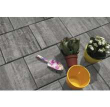 Graue Pflastersteine mit Blumenkelle und bepflanzten Blumentöpfen