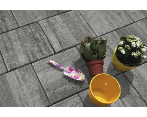 Graue Pflastersteine mit Blumenkelle und bepflanzten Blumentöpfen