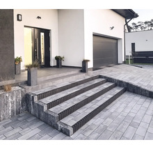 Außenansicht eines modernen Hauses mit gepflasterter Auffahrt und Treppe zum Eingangsbereich