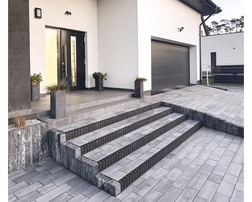 Außenansicht eines modernen Hauses mit gepflasterter Auffahrt und Treppe zum Eingangsbereich