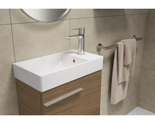 Badezimmerwaschtisch mit Armatur, Handtuch und Handtuchhalter.