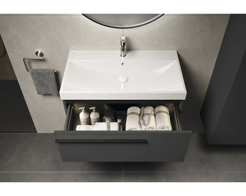 Waschtischunterschrank mit geöffneter Schublade, Waschbecken, Handtüchern und Pflegeprodukten im Badezimmer