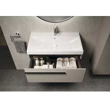 Badezimmerwaschtisch mit Schublade, Waschbecken, Handtuch und Armaturen unter einem Spiegel mit Beleuchtung