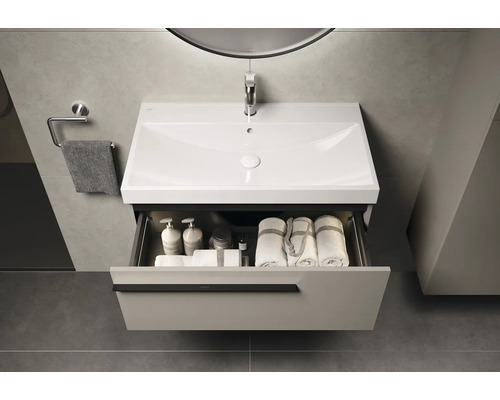 Badezimmerwaschtisch mit Schublade, Waschbecken, Handtuch und Armaturen unter einem Spiegel mit Beleuchtung