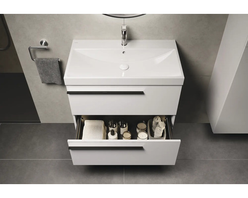 Modernes Badezimmer mit weißem Waschtischunterschrank und geöffneter Schublade, gefüllt mit Handtüchern und Badaccessoires.