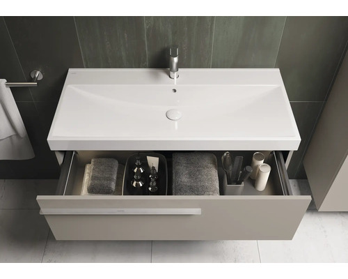 Badezimmer mit Waschtischunterschrank, Waschbecken, Armatur und offenem Schubladenfach mit Handtüchern und Badutensilien