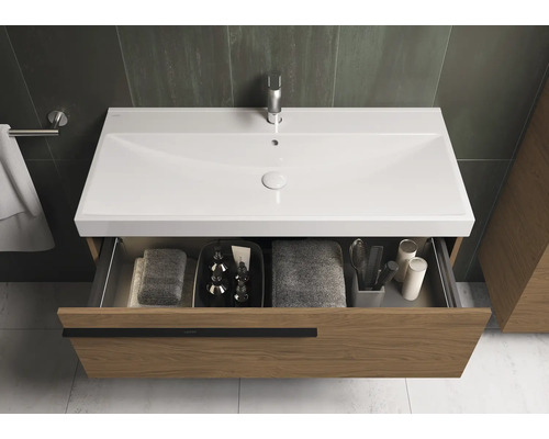 Waschtischunterschrank mit offenem Schubfach, ausgestattet mit Handtüchern und Badutensilien.