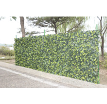 Blick auf eine grüne, künstliche Efeuhecke als Sichtschutz im Garten.