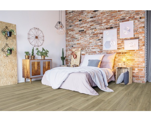 Schlafzimmer mit Holzboden, Bett, Kommode und Backsteinwand