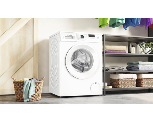 Weiße Waschmaschine von Bosch in einem Waschraum mit Wäschekorb und Regal