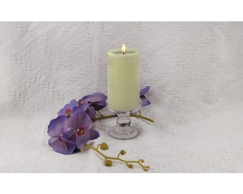 Dekorative gerippte Kerze auf einem Glasständer mit einer lila Orchidee