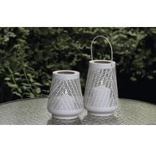 Zwei weiße Gartenlaternen mit Muster auf einem Tisch