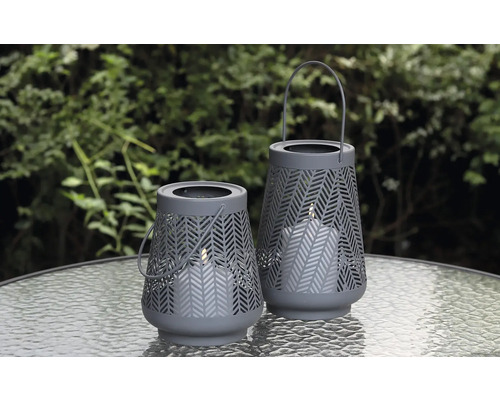 Zwei graue Windlichter mit Muster auf einem Tisch