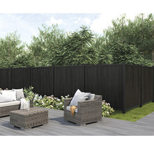 Gartenszene mit dunklem Sichtschutzzaun, Lounge-Möbeln und Bepflanzung