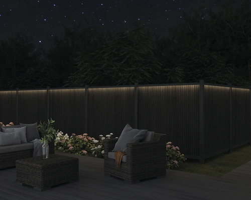 Gartenmöbel-Set auf Terrasse mit beleuchtetem Zaun bei Nacht