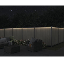 Garten mit beleuchtetem Zaun, Sitzgruppe und Blumen bei Nacht