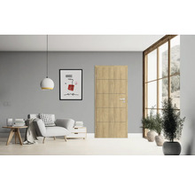 Wohnzimmer mit Holztür, Sessel, Beistelltisch, Kommode, Lampe, Fenster und Zimmerpflanzen für eine helle und freundliche Atmosphäre.