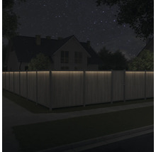 Holzzaun mit Beleuchtung vor einem Haus bei Nacht