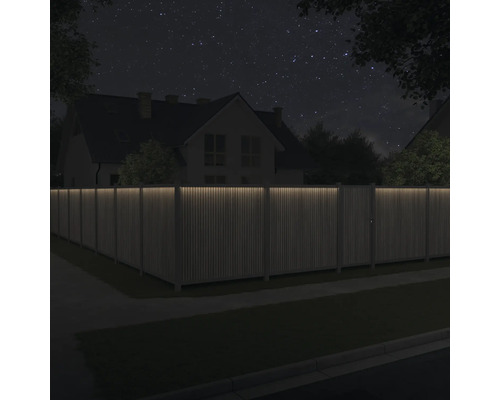 Holzzaun mit Beleuchtung vor einem Haus bei Nacht