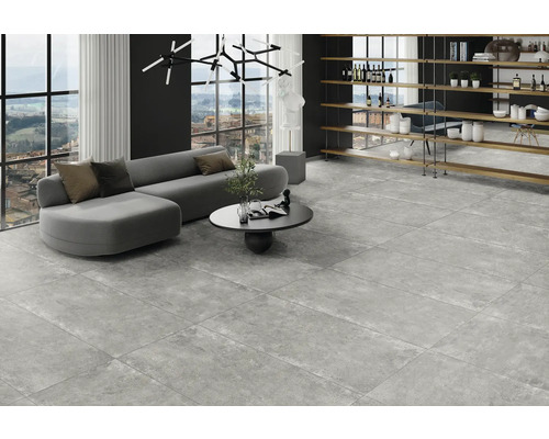 Heller Wohnraum mit grauem Sofa, Couchtisch und Bodenfliesen