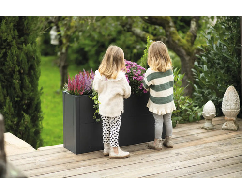 Szene mit zwei Kindern an einem Pflanzkasten im Garten