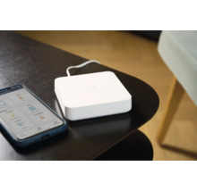 Intelligentes Haus System mit Smartphone-App und Zentraleinheit auf einem Tisch.