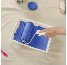 Farbe wird mit einer Farbwalze in eine Farbwanne aufgenommen