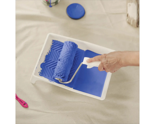 Farbe wird mit einer Farbwalze in eine Farbwanne aufgenommen