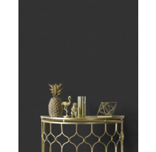 Dekorative goldene Ananas, Flamingo, Affe, Vase und geometrische Figur auf einem goldenen Beistelltisch vor einer dunklen Wand.