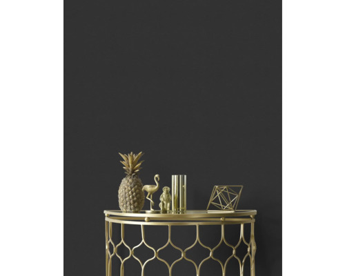 Dekorative goldene Ananas, Flamingo, Affe, Vase und geometrische Figur auf einem goldenen Beistelltisch vor einer dunklen Wand.