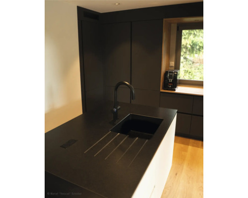 Küchenszene mit Spüle, Armatur und Küchengeräten vor dem Fenster