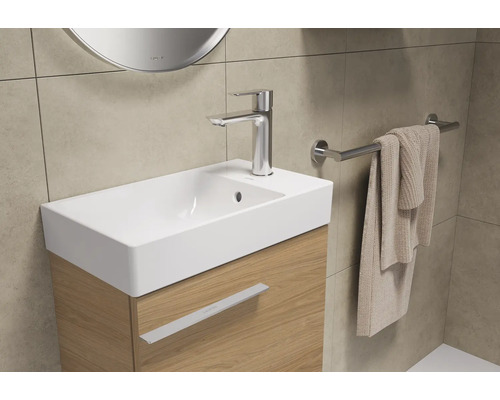 Waschtisch mit Armatur, Handtuchhalter und Handtuch in einem Badezimmer