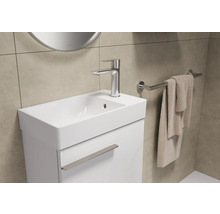 Waschtisch mit Armatur, Handtuch und Spiegel in einem Badezimmer.