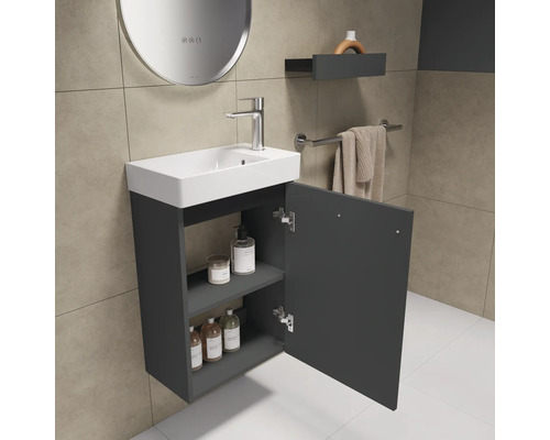 Badezimmer mit Waschbecken, Armatur und offenem Unterschrank zur Aufbewahrung von Badutensilien.