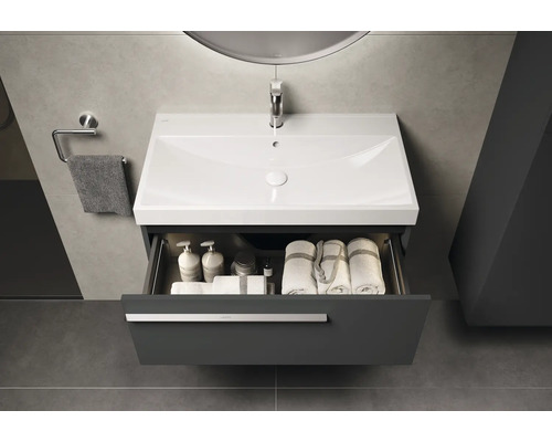 Waschtischunterschrank mit offenem Schubfach, ausgestattet mit Handtüchern und Pflegeprodukten, im Badezimmer