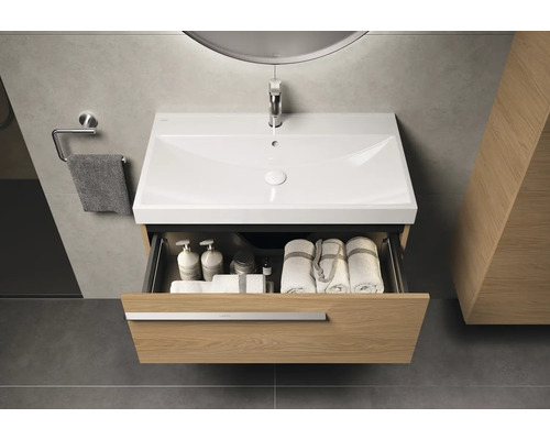 Waschtischunterschrank mit geöffneter Schublade, darin Handtücher und Badutensilien, Armatur und Handtuchhalter im Badezimmer