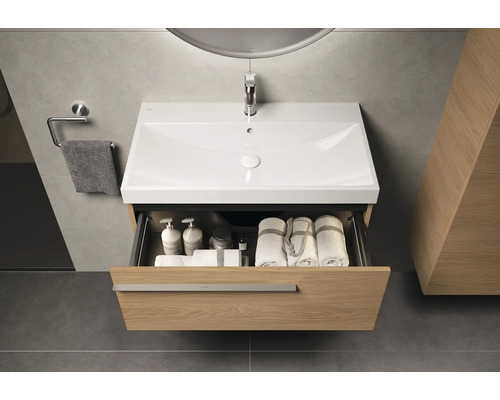 Waschtisch mit offenem Schubfach, darin Handtücher und Pflegeprodukte