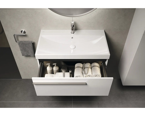 Waschtisch mit offenem Schubladen mit Handtüchern und Pflegeprodukten im Badezimmer.