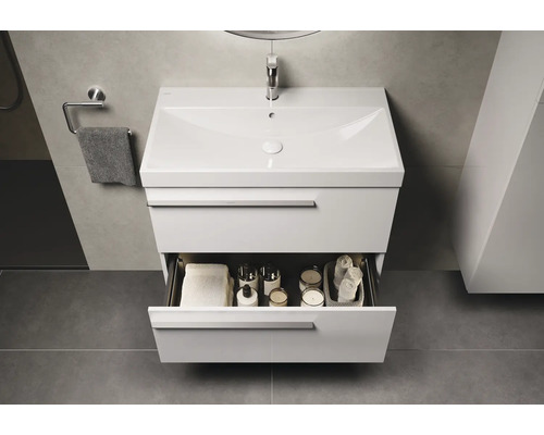 Waschtisch mit offenem Schubfach, darin Handtücher und Badutensilien