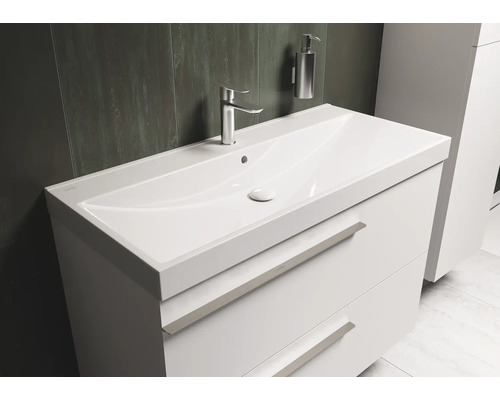 Waschtisch mit Unterschrank, Armatur und Seifenspender im Badezimmer.