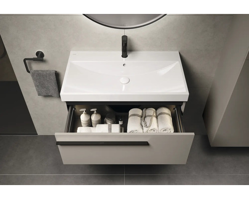 Waschtischunterschrank mit offenem Schubfach, Handtüchern und Pflegeprodukten im Badezimmer