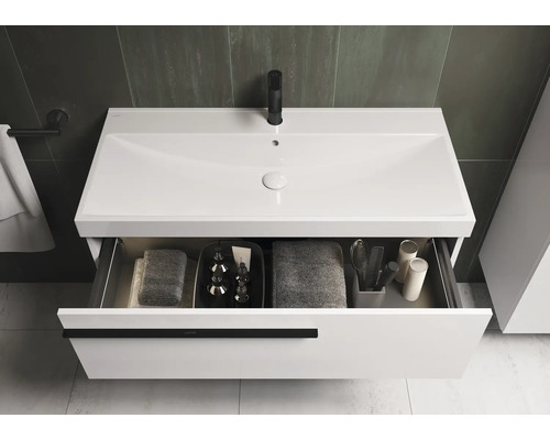 Waschtischunterschrank mit offenem Auszug und verschiedenen Badutensilien.