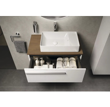 Modernes Badezimmer mit weißem Aufsatzwaschbecken auf Holzplatte und offenem Schubladenelement gefüllt mit Handtüchern und Pflegeprodukten.