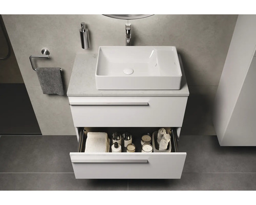 Modernes Badezimmer mit weißem Waschtischunterschrank, Aufsatzwaschbecken und geöffneter Schublade mit Badutensilien.