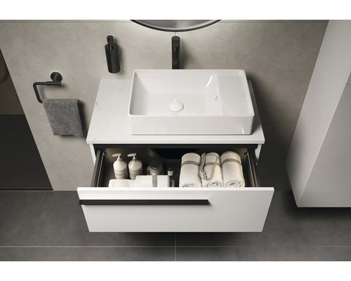 Modernes Badezimmer mit Waschtisch, rechteckigem Aufsatzwaschbecken und geöffneter Schublade mit Handtüchern und Pflegeprodukten.